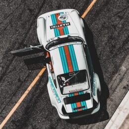 white, teal, and red sports car on park with door open during daytime